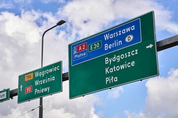 Low angle shot of green and blue square traffic signs in Poland on blue cloudy sky background