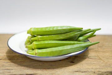 Pile of fresh okra on wooden background