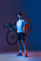 Portrait of professional cyclist in red sports uniform, goggles and helmet holding bike isolated on...