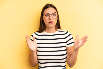 young adult pretty woman looking shocked and astonished, with jaw dropped in surprise when...