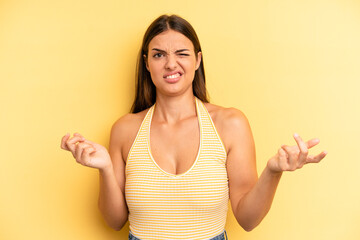 young adult pretty woman shrugging with a dumb, crazy, confused, puzzled expression, feeling...