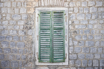 Aged wooden shutters on a window on a stone wall