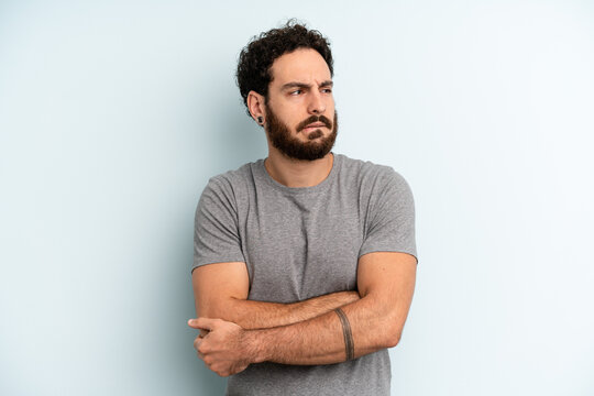 young adult bearded man doubting or thinking, biting lip and feeling insecure and nervous, looking to copy space on the side