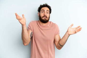 young adult bearded man shrugging with a dumb, crazy, confused, puzzled expression, feeling annoyed...