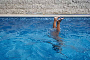 Child upside down underwater in the pool, legs out of the pool