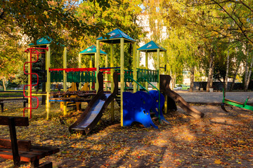 Colorful playground equipment for children in public park at autumn