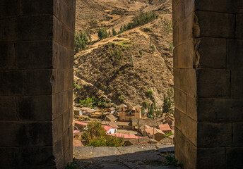 
trapezoidal stone door with church and yellow grass in the background