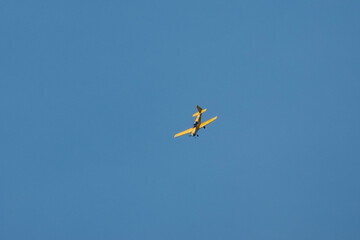 small bright yellow microlight plane with a blue sky background