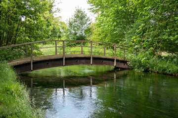 rustic wooden and metal bridge over a beautiful chalk river in Hampshire England