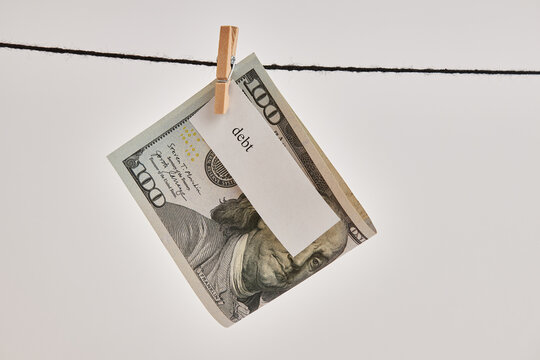 A $100 bill with the words "debt" on it hung on a clothesline.