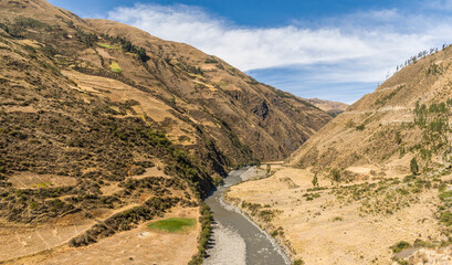river near yellow mountains with cloudy sky in the background