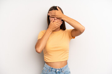 hispanic pretty woman covering face with both hands saying no to the camera! refusing pictures or...