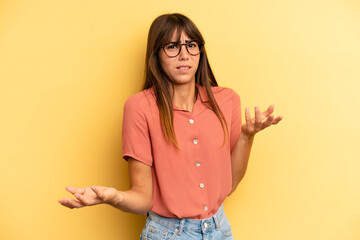 hispanic pretty woman shrugging with a dumb, crazy, confused, puzzled expression, feeling annoyed...