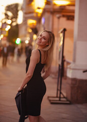 Smiling blond woman posing in fashion style clothes walking on city street summer night lights background. outdoor portrait. Blur unfocus art portrait.  vintage