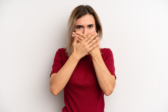 young adult blonde woman covering mouth with hands with a shocked, surprised expression, keeping a secret or saying oops