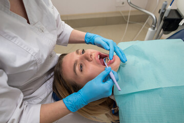 Dentist-hygienist conducts a teeth cleaning procedure for a girl in a dental clinic. Removal of tartar.