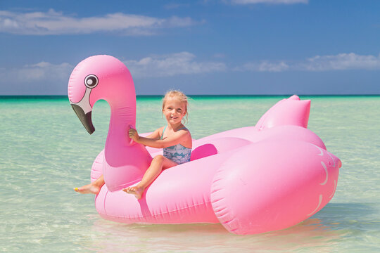 Little Girl On Inflatable Flamingo On The Sea. Travel Lifestyle, Swimming Activities In Family Summer Camp. Summer Vacations 2020 On Tropical Island After Coronavirus Covid-19 Lockdown Concept