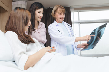 An expert doctor is explaining the X-ray results from the X-ray film to the patient and their relatives in the hospital room.