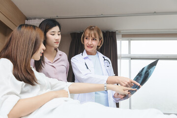 Obraz premium An expert doctor is explaining the X-ray results from the X-ray film to the patient and their relatives in the hospital room.