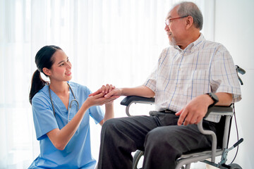Obraz premium Asian nurse or doctor sit on floor and hold hands of senior man sit in front of curtain in living room.