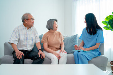 Obraz premium Asian nurse or doctor discuss with senior man and woman in living room with concept of home care worker support and modern business.