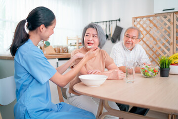 Nurse or doctor who work as homecare staff help to serve a spoon of mush rice to senior woman with...