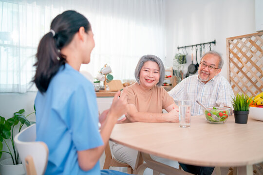 Nurse Or Doctor Help To Explain And Give Medicine To Senior Man During Process Of Health Support For Home Care And They Stay In Kitchen Of House.