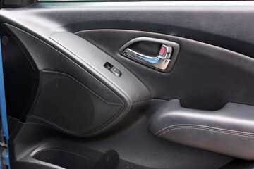 Lux Car interior. Car door trim, door handle and control buttons. Front door panel. Lux car door handle and control buttons.