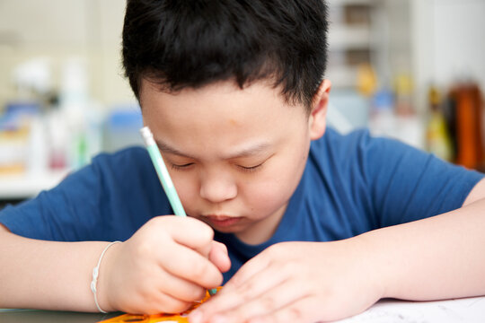 asia boy concentrating to write book