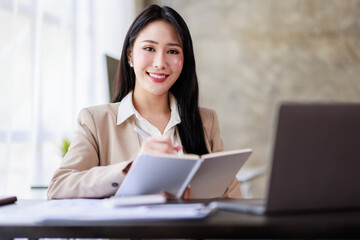 Asian Businesswoman working on laptop at the office with documents on his desk, doing planning analyzing the financial report, business plan investment, finance analysis concept