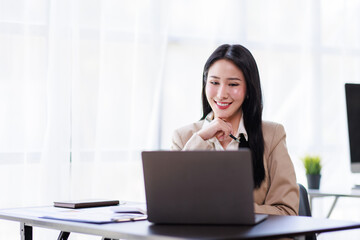 Asian Businesswoman working on laptop at the office with documents on his desk, doing planning analyzing the financial report, business plan investment, finance analysis concept