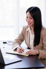 Asian Businesswoman working on laptop at the office with documents on his desk, doing planning analyzing the financial report, business plan investment, finance analysis concept