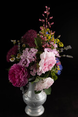 Blurred image of a bouquet with pink roses in a vase on a black background.