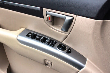 Door handle with windows controls and adjustments in light leather interior. Window switches.