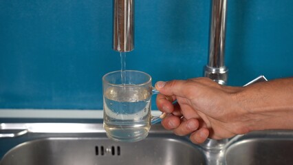 open the water tap at home in the kitchen and fill a glass - waste of drinking water in homes in...