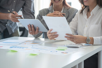 Team of business use calculators and graph analysis computer laptop tablets to plan marketing strategies and make profitable investments for the company.