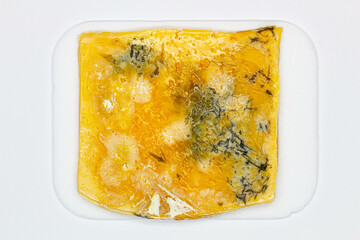 Cheese with mold. A large sliced piece of cheese with holes, long been spoiled and covered with mold. Beautiful view of spoiled food. Yellow moldy cheese. Blue cheese. Milk product. Close-up. Top view