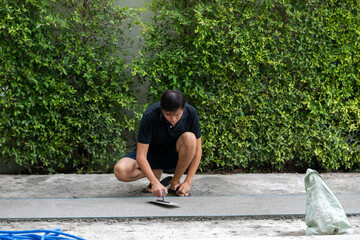 man working on explsed aggregate finish the front of the house