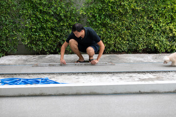 man working on explsed aggregate finish the front of the house