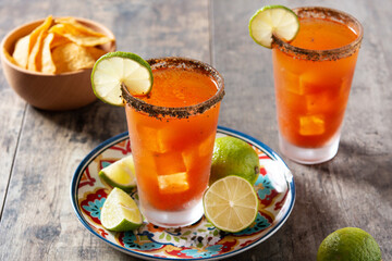 Homemade michelada cocktail with beer, lime juice,hot sauce,salted rim and tomato juice on wooden table	