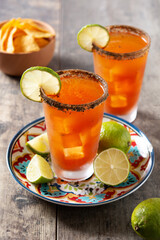 Homemade michelada cocktail with beer, lime juice,hot sauce,salted rim and tomato juice on wooden table	