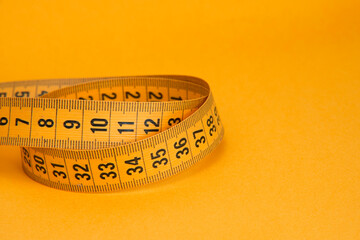 Orange tape measure diet concept on background with copyspace