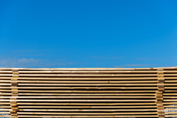 Wooden boards for construction stacked outdoors under a bare sky, horizontally, building material