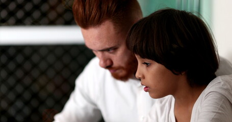 Parent and child bonding together in front of laptop computer. Ethnic diverse family