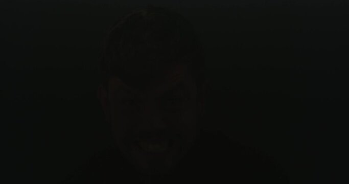 Face portrait of schizophrenic patient against flashing black background in studio with copy space. Insane, angry, crazy or mentally ill man screaming and shouting while suffering from schizophrenia
