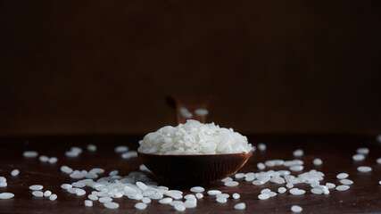 Rice and wooden spoon on black background. Photo with copy space.