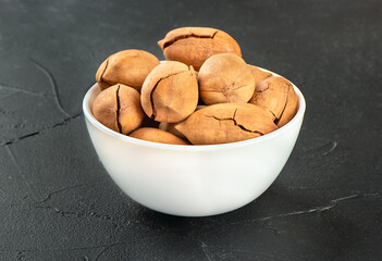 White ceramic bowl with pecans on a dark background