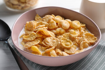 Tasty cornflakes with milk in bowl on table, closeup