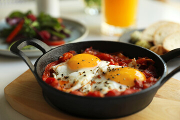 Tasty Shakshouka served in pan on table, closeup