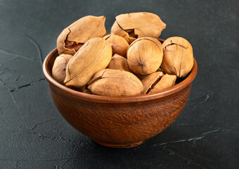 Pecan nuts in a bowl on a dark concrete background